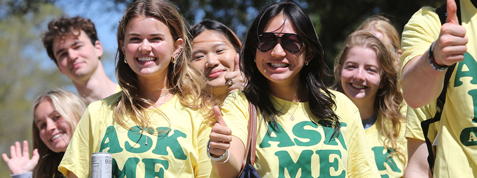A group of smiling students wearing Ask Me About W&amp;M t-shirts pose together